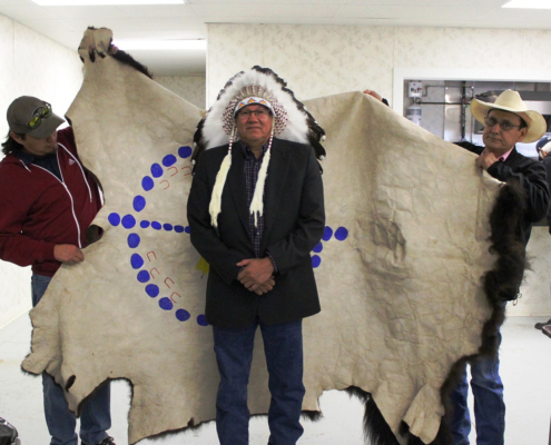 Blackfoot Confederacy Conference Council members Kyle Grier and Casey Scott presenting Chief Charles Weasel Head the Blackfoot Confederacy Robe